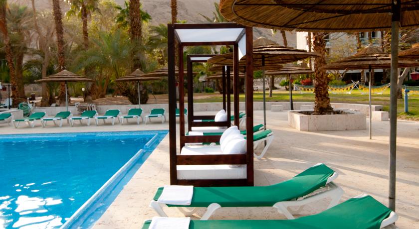 Лежаки у бассейна с зонтиками и навесами